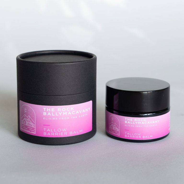 A black cylindrical container and a small black jar, both with pink tallow barrier balm labels, are displayed on a light gray surface.