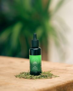 the front of a green bottle of root ritual hair oil