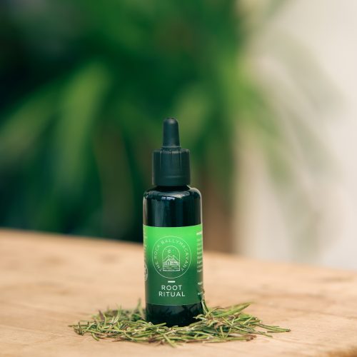 the front of a green bottle of root ritual hair oil