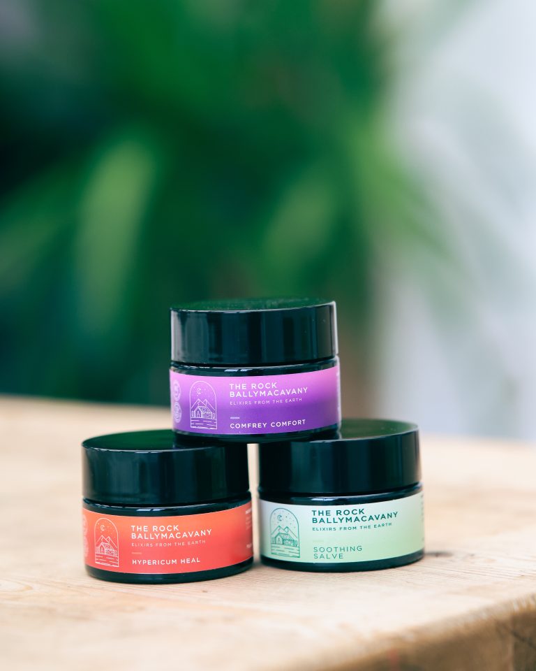 3 containers of salves, stacked in a pyramid, with hypericum heal on the bottom left, soothing salve on the bottom right, and comfrey comfort sitting on top of both